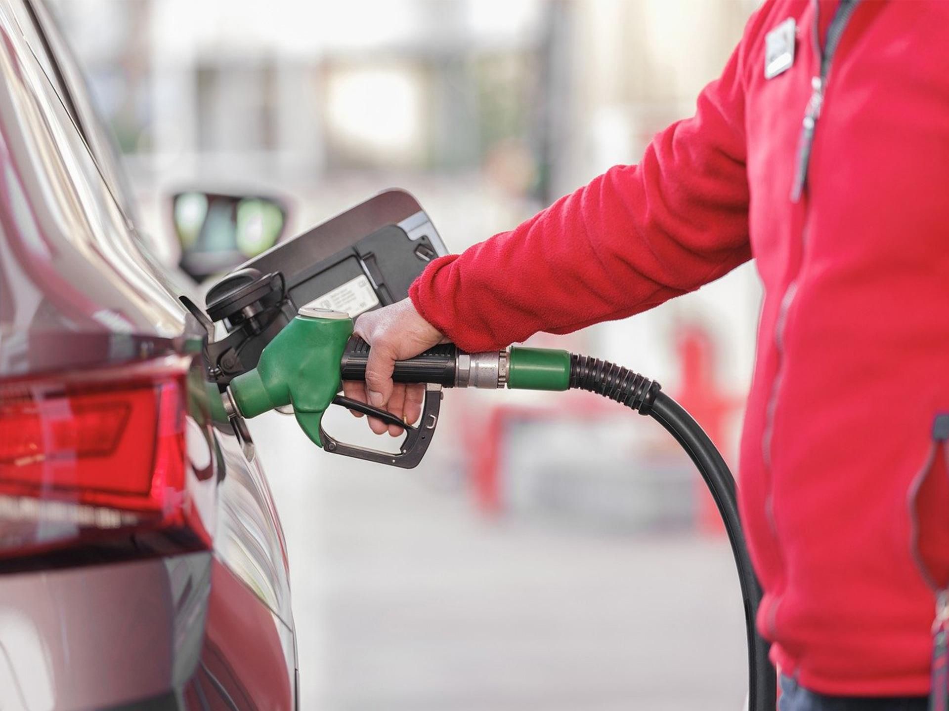 uomo con tuta rossa che fa benzina a una stazione di servizio