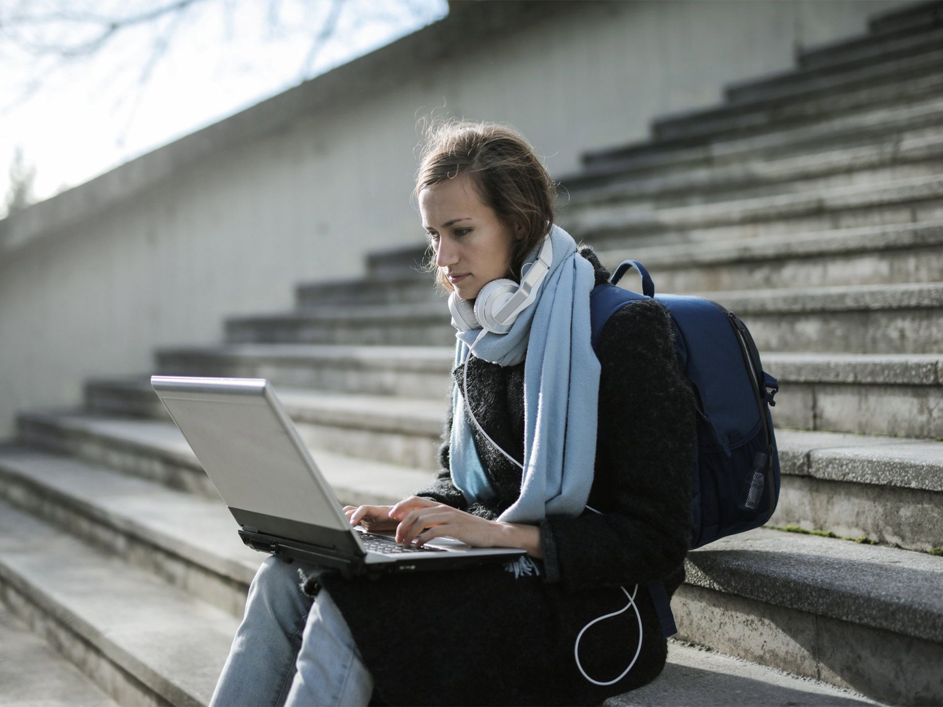 ragazza seduta su scalinata all'aperto con laptop sulle ginocchia
