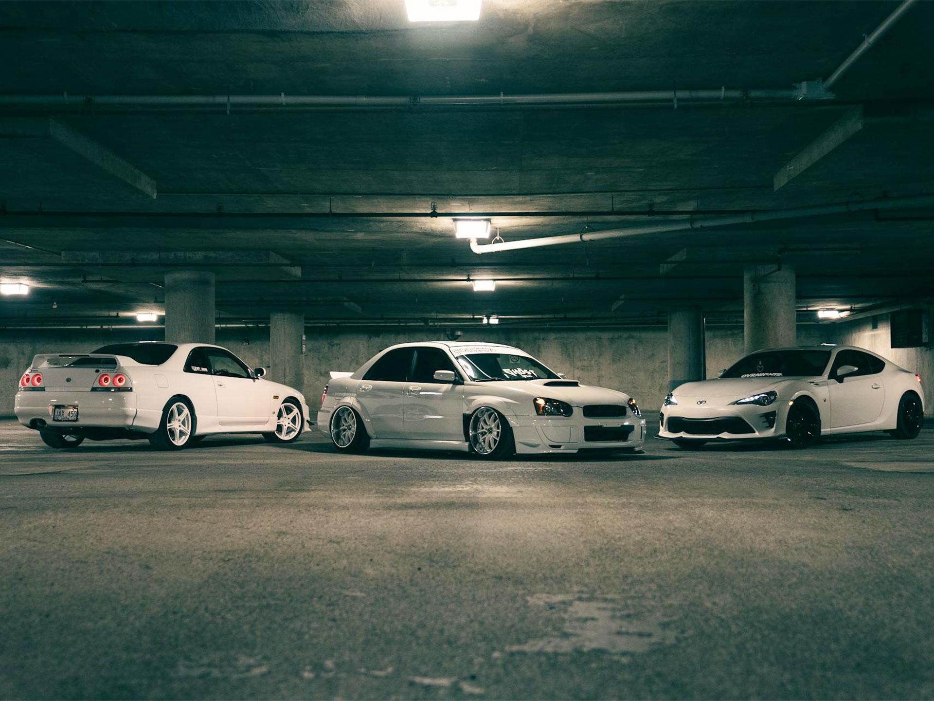 tre automobili bianche parcheggiate e illuminate dall'alto da luci bianche