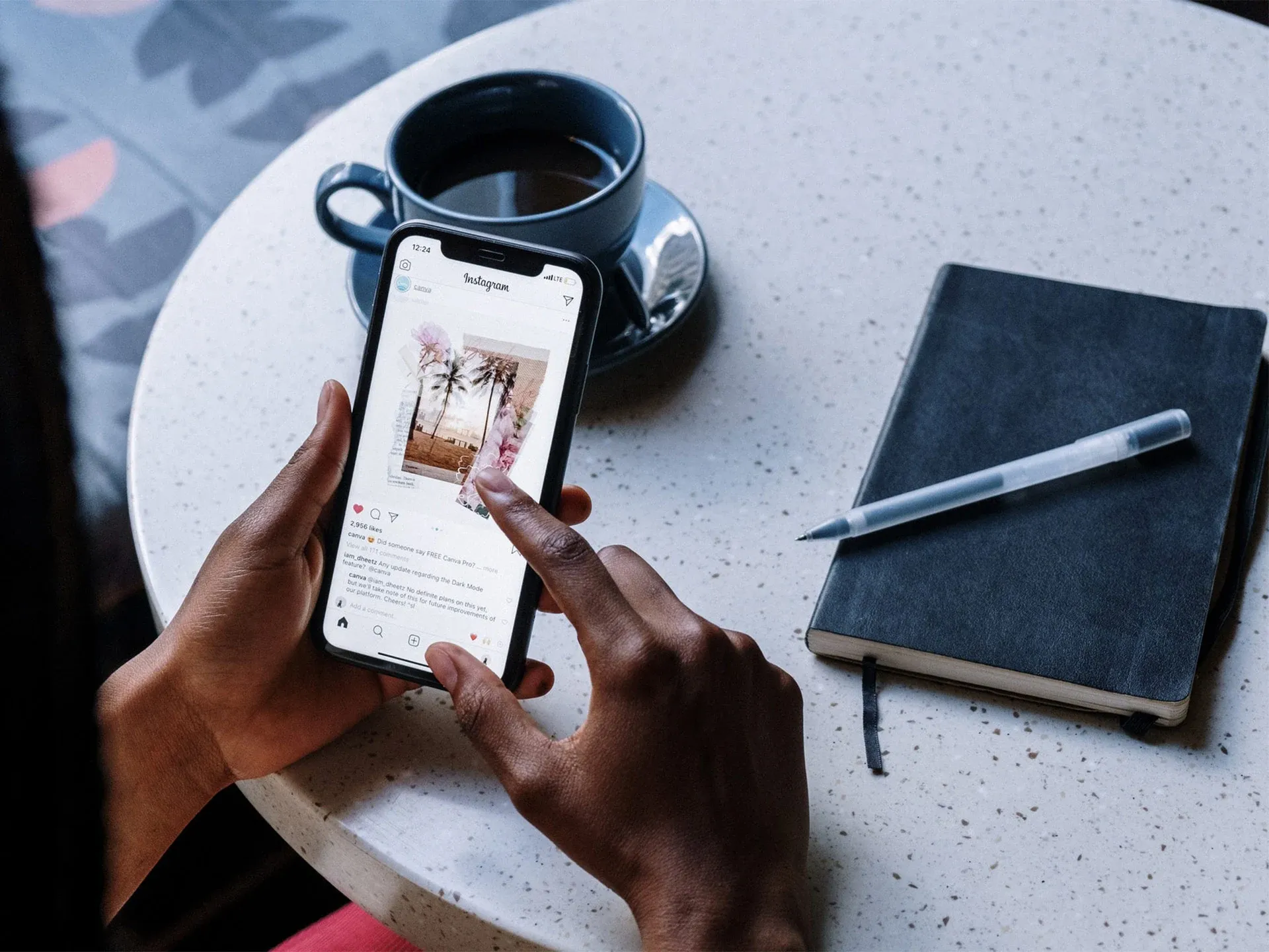 dito che scrolla feed di Instagram su un cellulare con tazza di caffè e agenda sullo sfondo