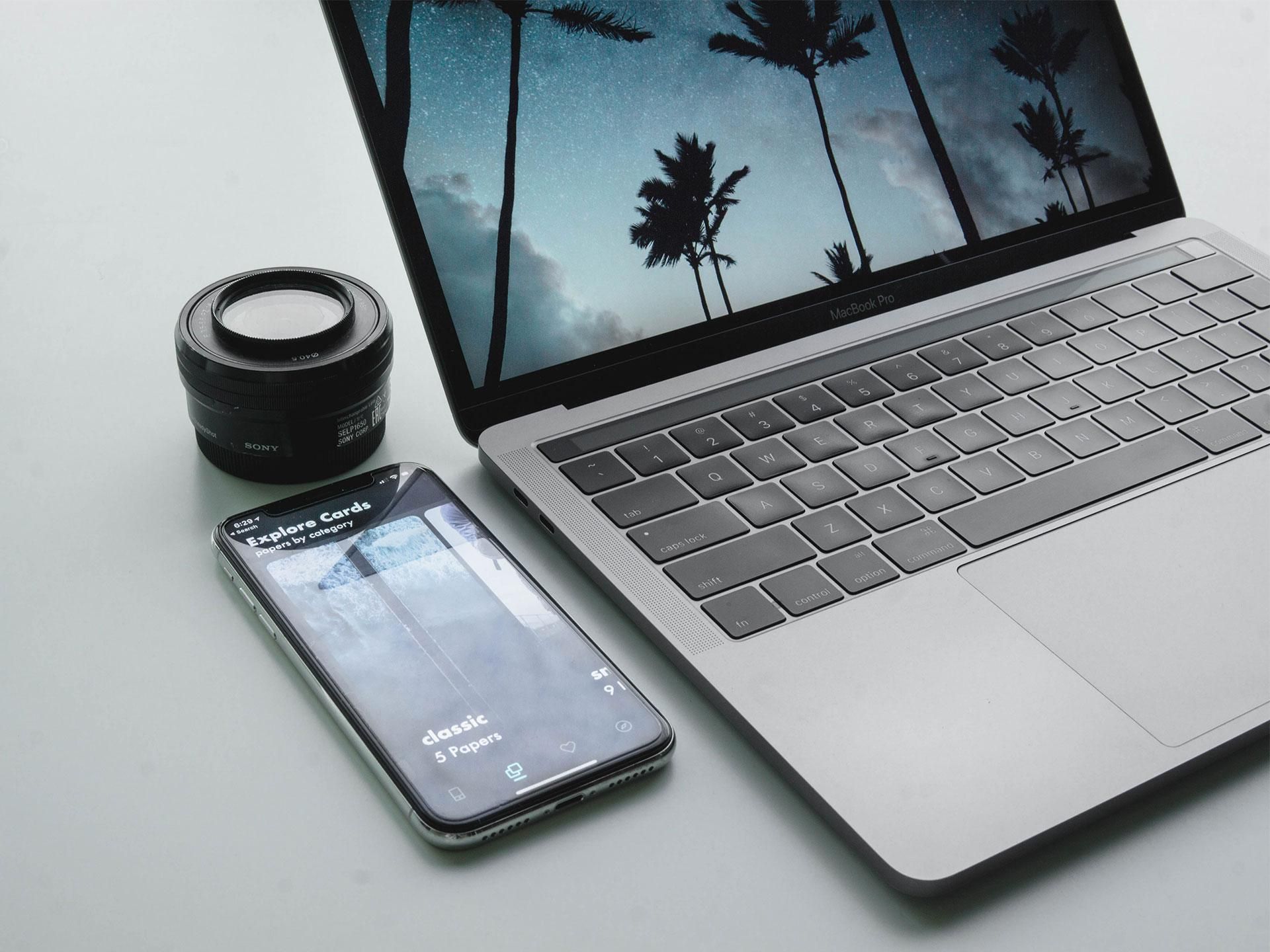 laptop, smatphone e obiettivo fotografico sopra una superficie chiara