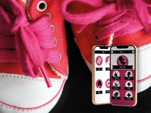 Scarpette rosse allacciate e due smartphone con aperta l'app Mamma&Co.