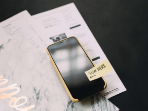 Smartphone con attaccato un post-it in cui c'è scritto Sign here