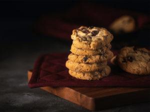 biscotti con gocce di cioccolato sopra un tagliere di legno coperto da un tovagliolo rosso