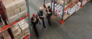 interno di magazzino visto dall'alto con tre persone che camminano tra gli scaffali