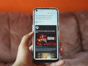 mano che regge uno smartphone su uno sfondo marrone e arancio