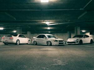 tre automobili bianche parcheggiate e illuminate dall'alto da luci bianche