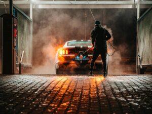 uomo di spalle lava auto scura con l'idropulitrice